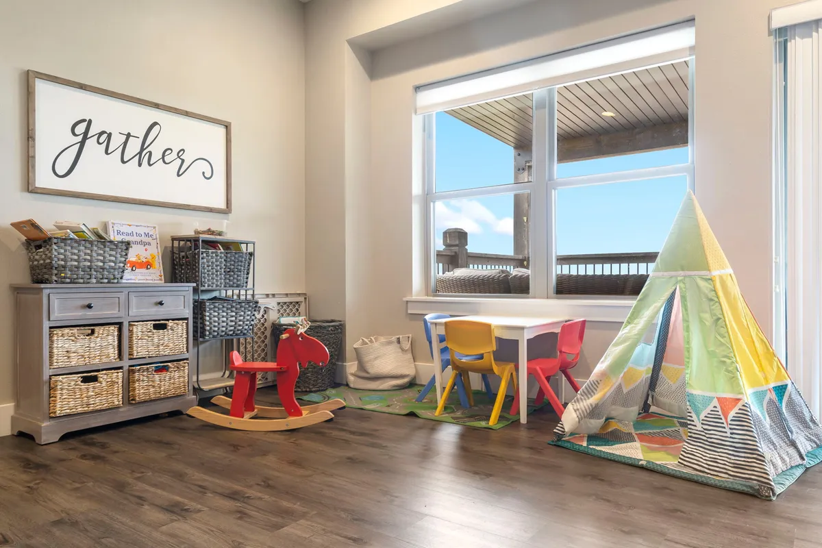 A cheerful kids’ play corner featuring a colorful play tent, children's table and chairs, a rocking horse, and inviting storage baskets. The area is playful and integrated into the broader living space, ensuring young guests have their own space.