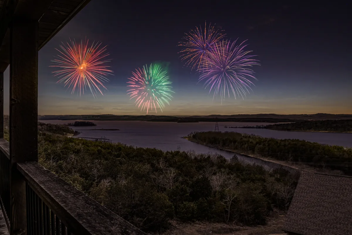 A festive scene featuring fireworks over the lake, with rolling hills in the distance and a celebratory atmosphere. The image captures a moment of community gathering and the excitement of special events enjoyed in the area.