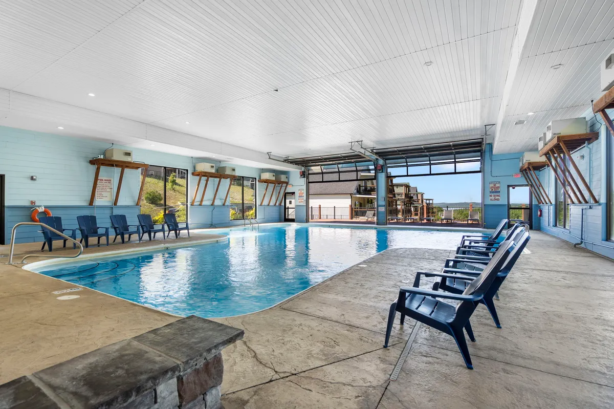This interior image showcases the year-round indoor pool, surrounded by large windows letting in natural light and comfortable lounge chairs. The setting is tranquil and provides a refreshing escape in any season.