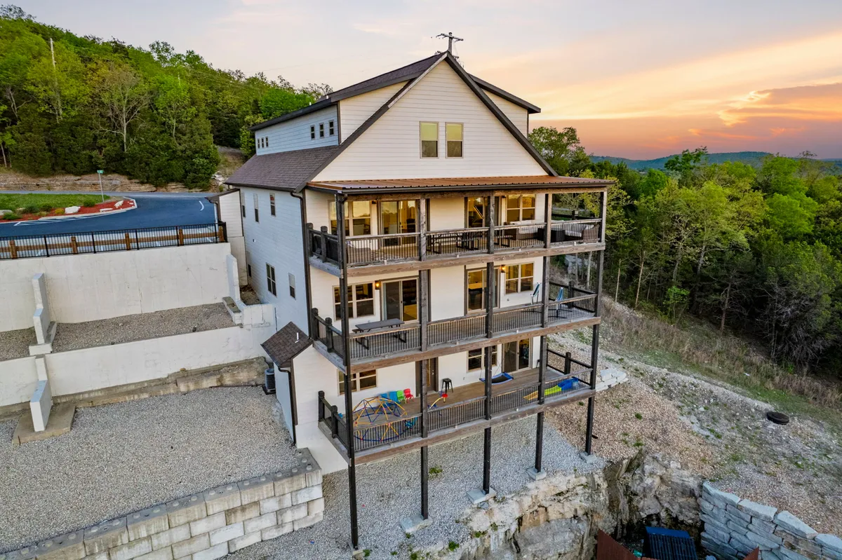 An inviting exterior shot captures the multi-level balconies of The WOW Factor at Chateau Cove, set against the backdrop of a vibrant sunset sky. The property's architectural details and its integration with the surrounding natural landscape are clearly visible.
