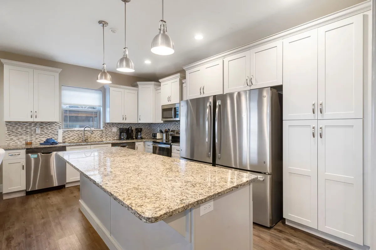 A chef-inspired kitchen with a large island, stainless steel appliances including double refrigerators, and ample granite counter space. The layout is ideal for meal prep and social cooking experiences.