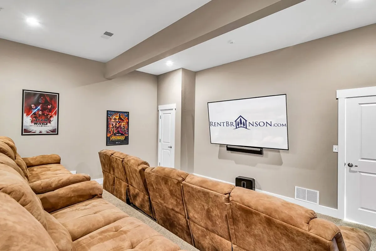 A dedicated theater room interior with comfortable seating, a large screen TV, and movie posters decorating the walls, creating a true cinematic atmosphere ideal for movie nights or sports viewing.