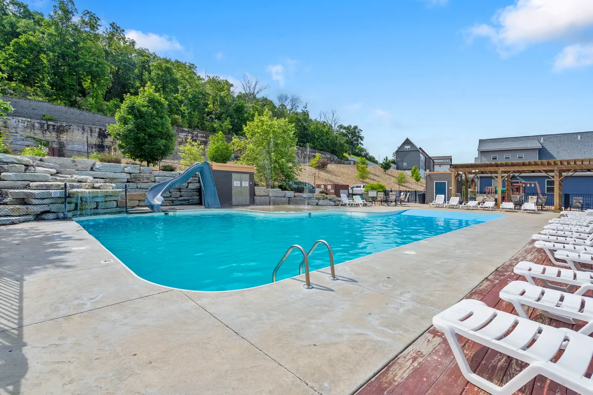 This image features the resort's outdoor swimming pool, complete with a water slide, lounge chairs, and lush landscaping. The pool is set in a sunny, cheerful environment that highlights the vibrant atmosphere of the resort's amenities.
